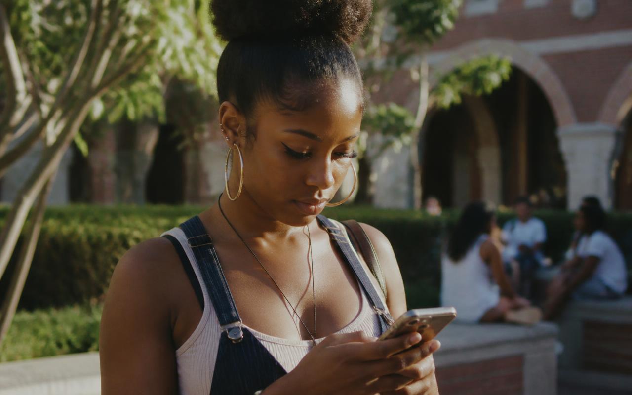 A employee reading a message on her phone in a sunlit courtyard